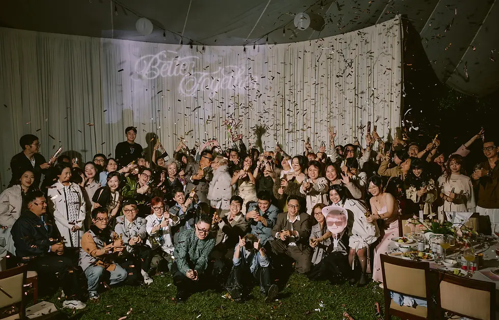 Ảnh tập thể đông người bắn confetti trong tiệc cưới buổi tối, ghi lại khoảnh khắc sôi động và bùng nổ cảm xúc.