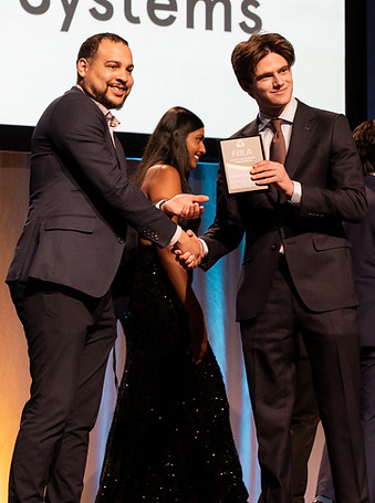 A student receiving an award plaque from a Colorado FBLA sponsor on stage and smiling