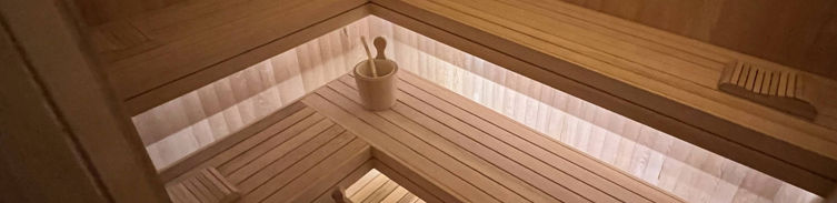 Sauna con bancos flotantes iluminados desde abajo con luz tenue blanca.