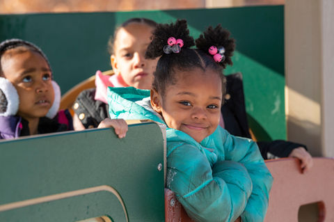Three children playing, one smiling at camera