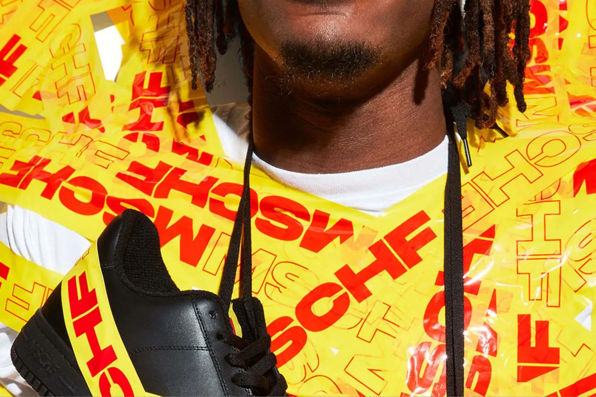 MSCHF campaign image featuring model wrapped in yellow caution tape, showcasing conceptual fashion drop blending streetwear and satire