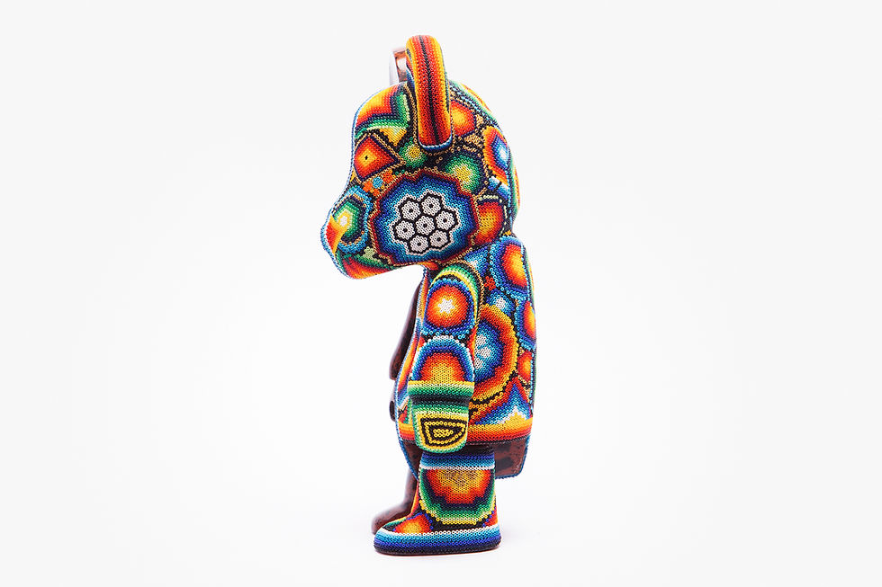Colorful bear figurine with intricate bead patterns stands in profile against a white background, displaying vibrant geometric designs.