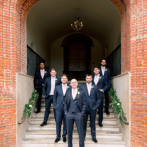 Groomsmen posing together beneath a brick archway