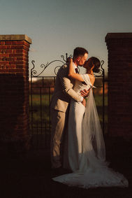 Bride and groom embracing beside a wrought-iron garden gate at Lillibrooke Manor.