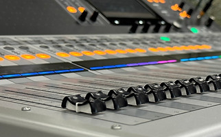 Colored photo of a Yamaha TF5 digital mixing console being used by a marching band to enhance their field show.