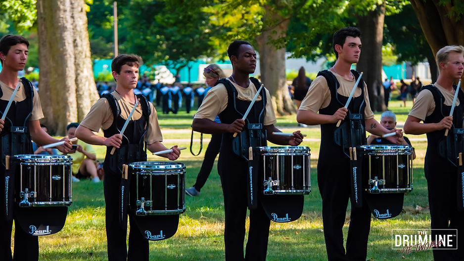 a group of drummers playing the snare drum together in a park