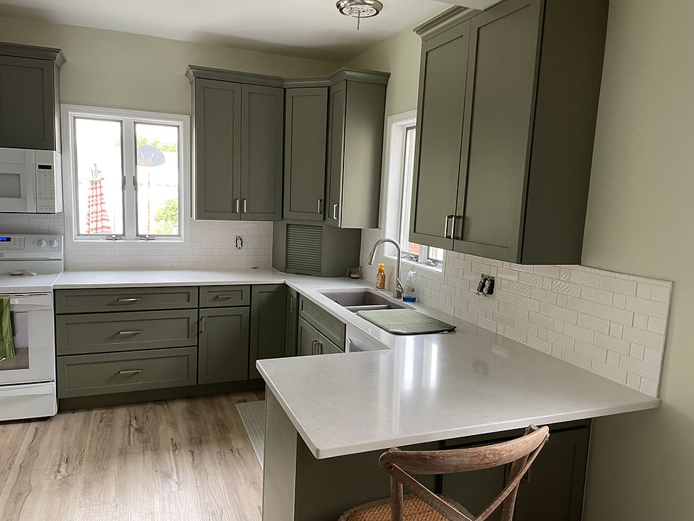 Modern kitchen with green cabinets and white countertops in a home.