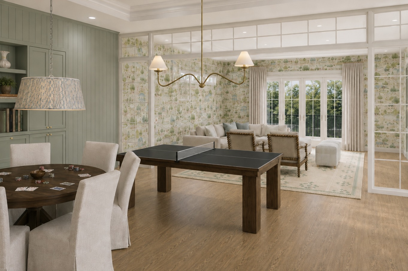 A game room with sage millwork, tree wallpaper, a card table, and a ping-pong table opening onto a sunlit sitting area.