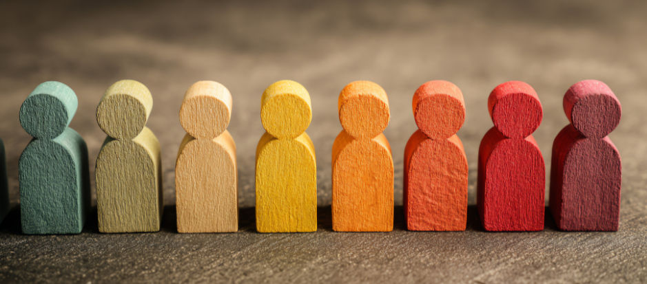 Colorful wooden figures in a row, in rainbow colors showing the diversity of students in schools.
