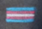 Transgender flag drawn in chalk on asphalt. Blue, pink, and white stripes are visible. The texture is rough and gritty.