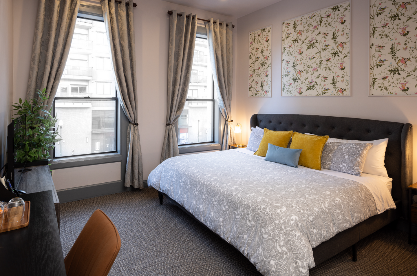 Bedroom with large bed, two windows, and floral wall art