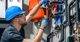 A man installs a heating system in a house and checks the pipes with a wrench._edited.jpg