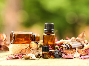 Selection of various sized amber bottles on wooden surface with dried flowers and leaves.