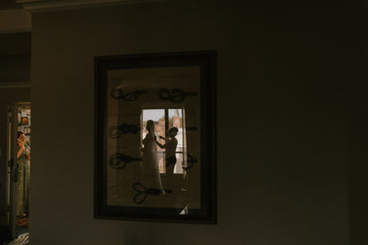 Annapolis bride gets ready in the reflection of a painting at Graduate Hotel Annapolis