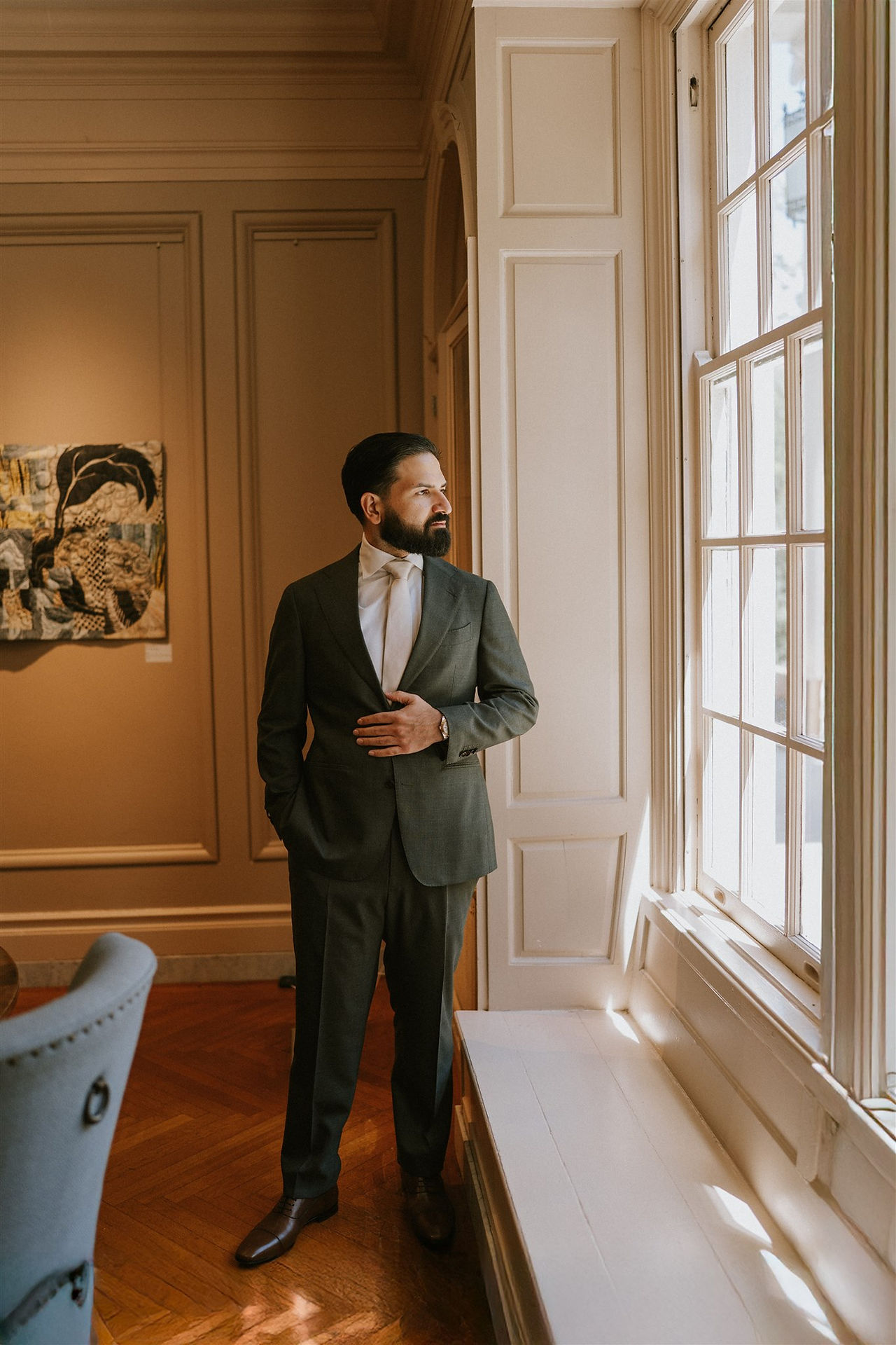 a groom staring out the window before walking down the aisle 