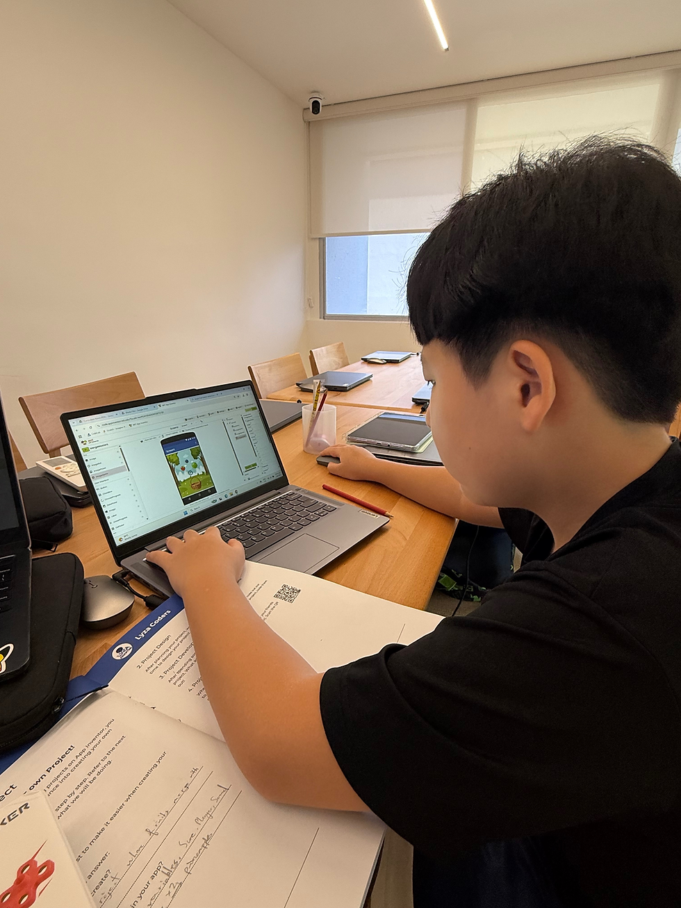 Student coding out a MIT App Inventor project with a laptop