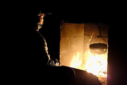 man in front of fire with a pot over it