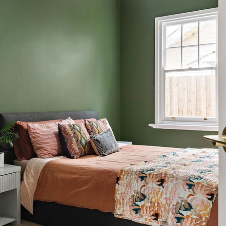 Renovated bedroom with deep green walls and a restored white timber double-hung sash window