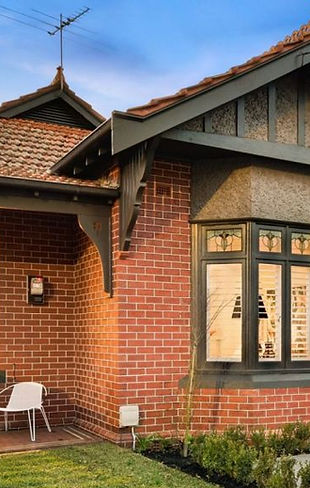 Restored red brick Edwardian home in Melbourne with leadlight bay window, gabled porch and terracotta tiled roof