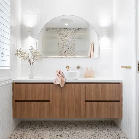 Bathroom renovation with terrazzo floor, timber wall-hung vanity, arched mirror and brass tapware