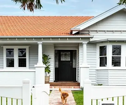 White weatherboard Californian bungalow with terracotta tiled roof and columned porch