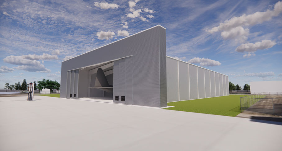 Modern gray hangar building with open door, large paved area, blue sky.