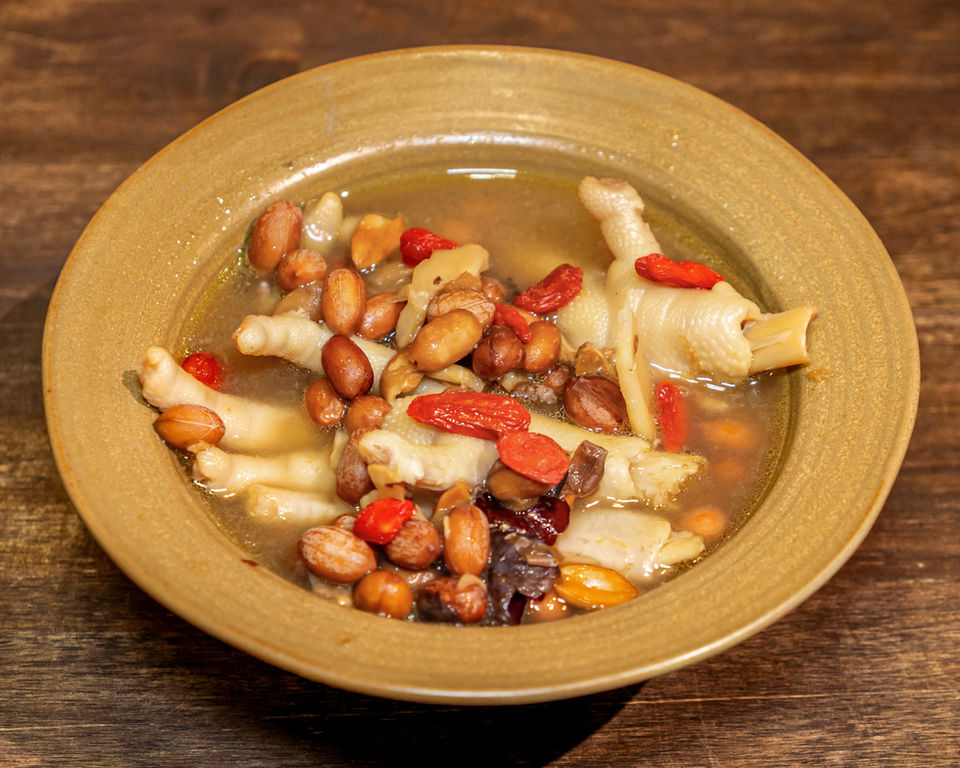 Chicken feet soup with peanuts and goji berries in a bowl.