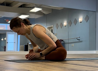 Woman practicing seated yoga pose in a studio mirror at yoga sol