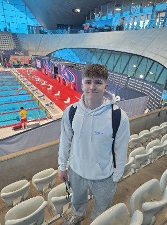 boy in the stands inside a swimming pool with pool in background