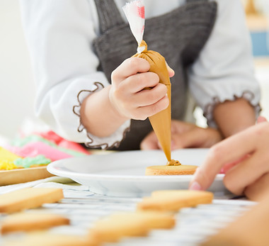 Close up on hands. Happy Asian Kid and young mother decorating cookies in the kitchen..jpg
