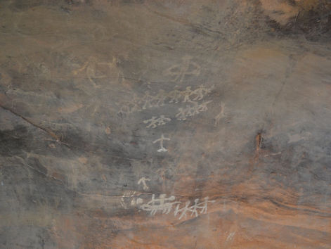 Prehistoric stick figures dating back roughly 30,000 years with raised arms and bent legs on the Bhimbetka rock shelters