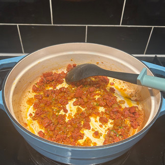 Blue pot with, black spoon with blue handle with onions,garlic and chorizo mixed and cooking together