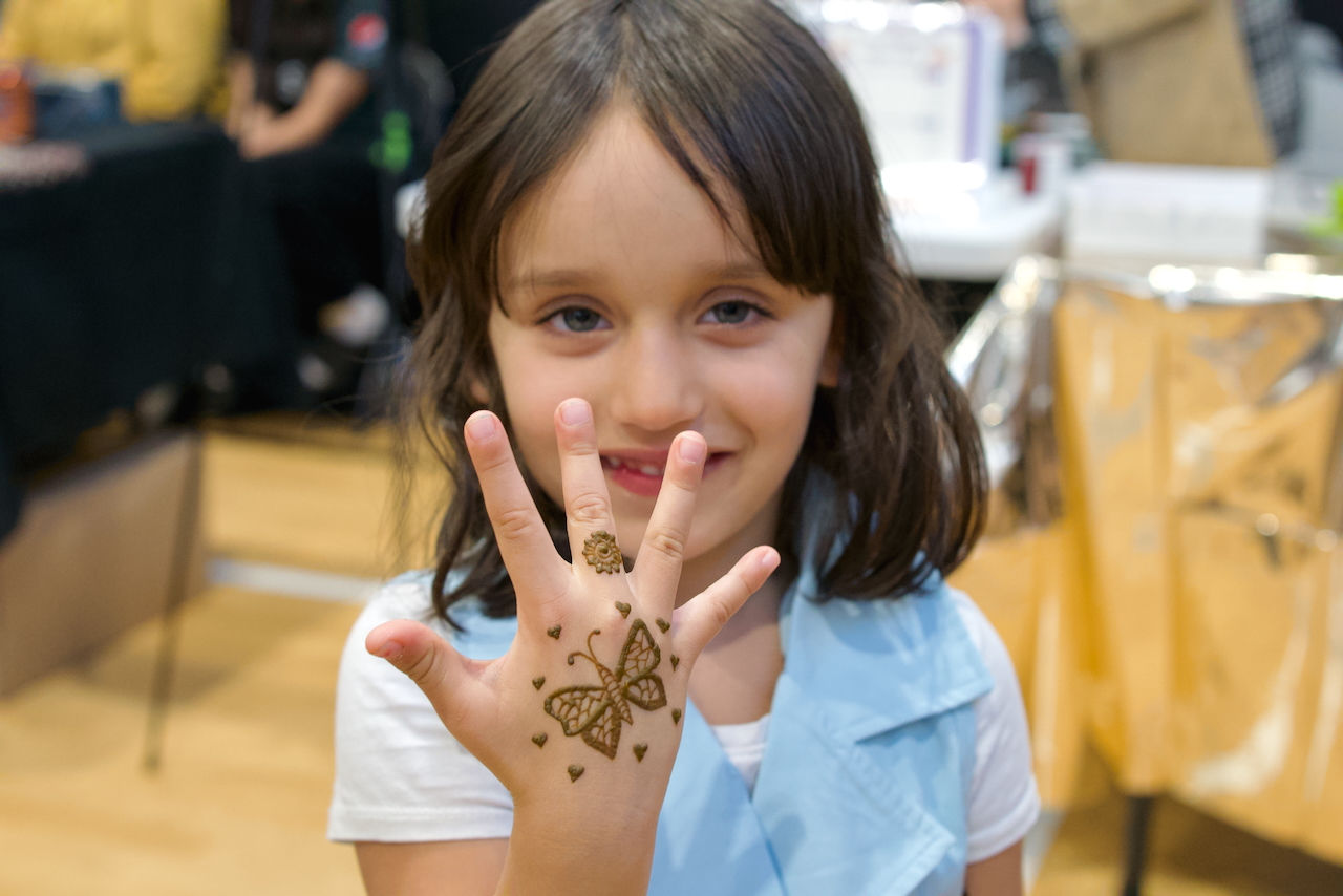 Little girl showing henna at an Eid event in London, Ontario, celebrating with traditional decorations and festive attire