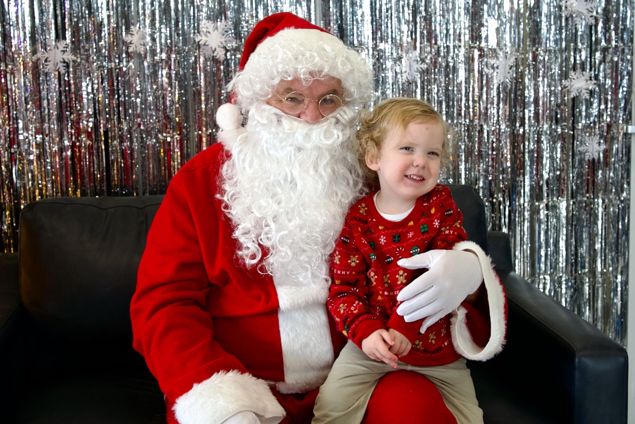 kid getting excited while sitting with santa and getting his picture