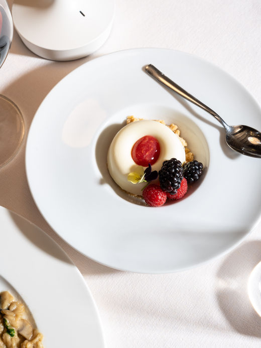 Panna cotta con coulis di frutti di bosco e decorazione elegante, fotografia food per ristoranti gourmet