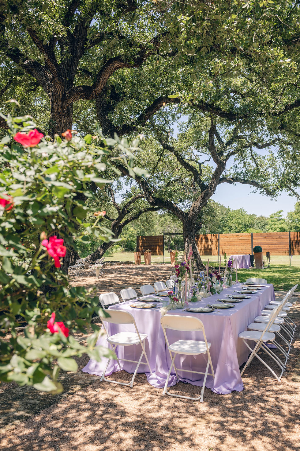 a king table covered in bud vases and candle sticks is set in the garden area of hidden creek at StoneHaus for a lavender micro wedding in May