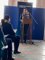 A man giving speech at a podium in front of a crowd.