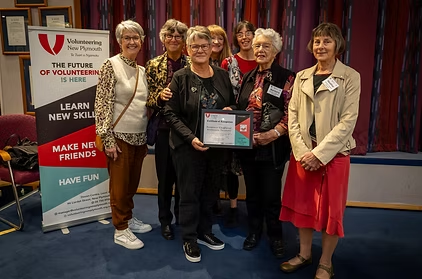 A group of smiling women centred around one woman holding a certificate