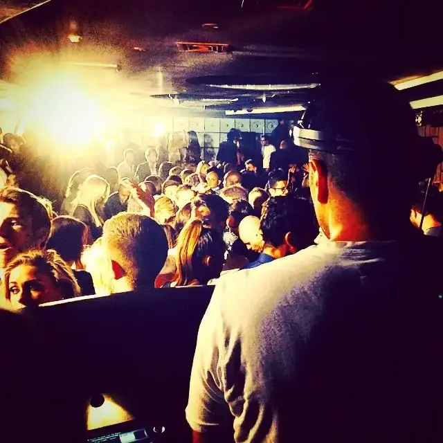 Maddox Club London guestlist and table clients dancing in the background with the DJ in the foreground.