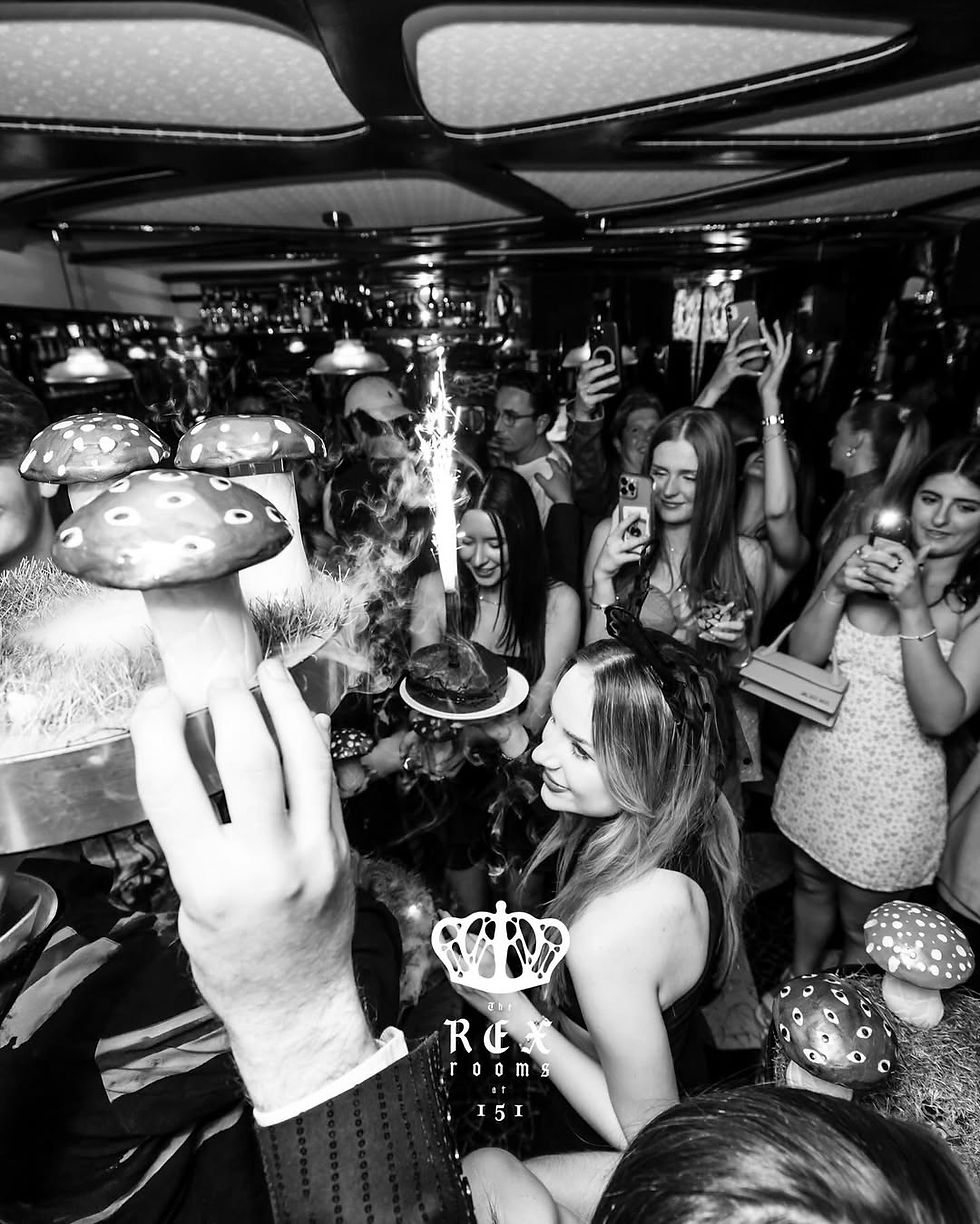 Rex Rooms Club Chelsea guestlist clients enjoying a champagne show with sparklers and mushroom-shaped shot glasses.