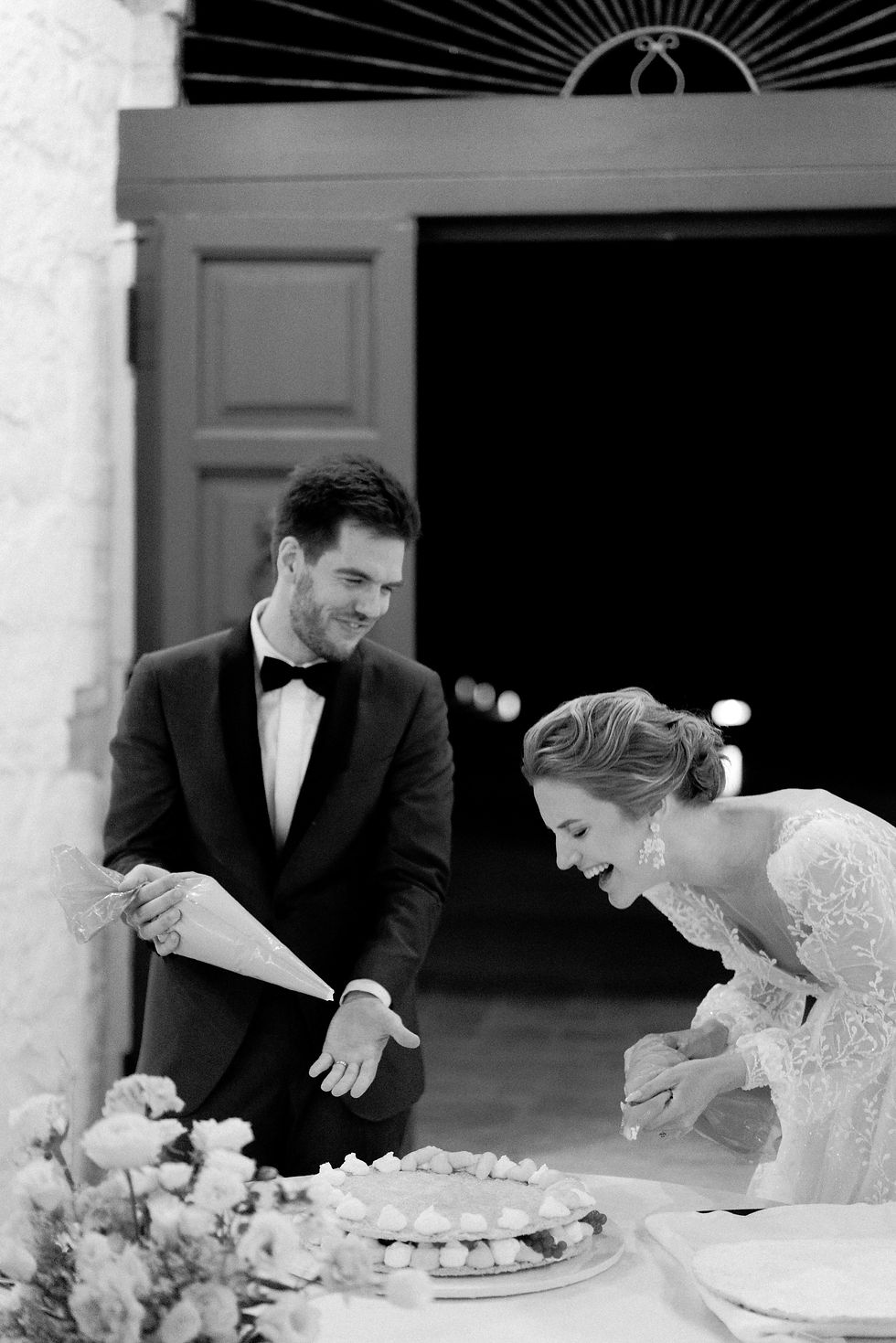 Un couple de mariés rit aux éclats en découpant son gâteau de mariage