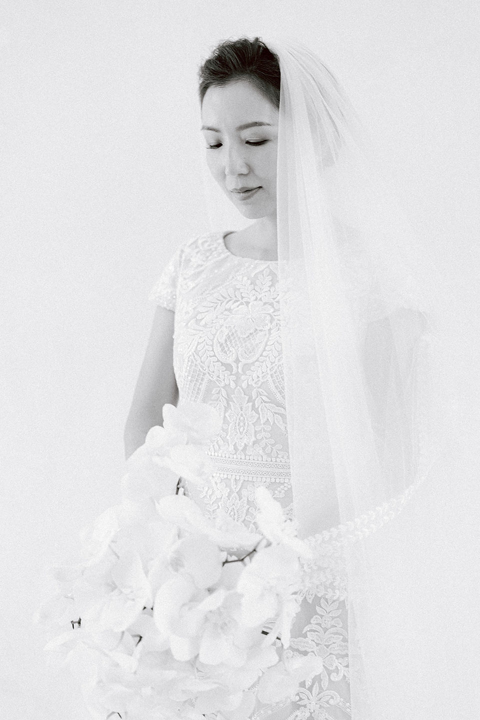 Portrait en noir et blanc d'une mariée devant un mur blanc