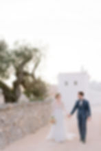 Des mariés marchent au coucher du soleil devant une masseria le jour de leur mariage en Italie