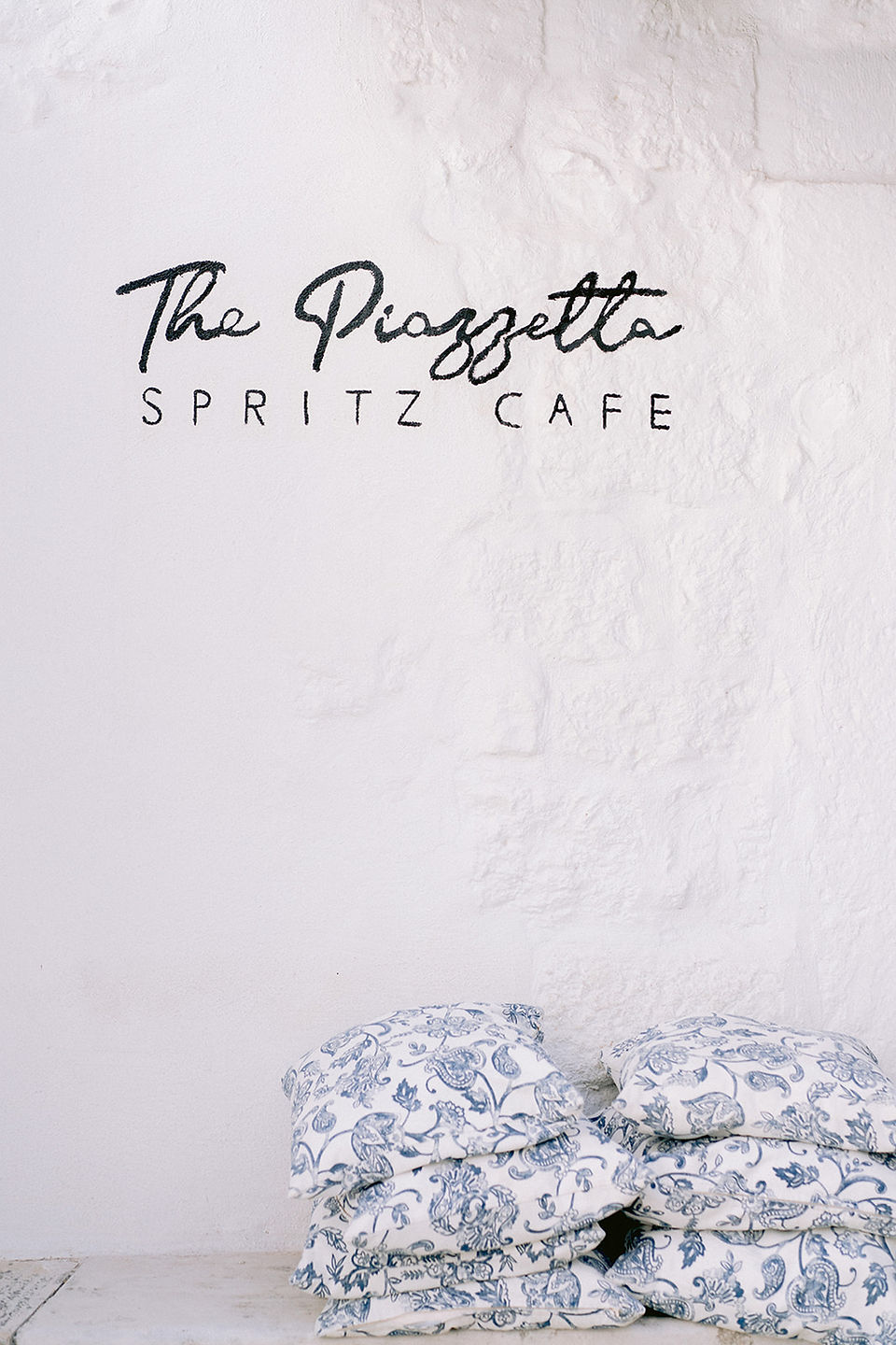 Le nom d'un café est peint en noir sur un mur blanc à Ostuni en Italie