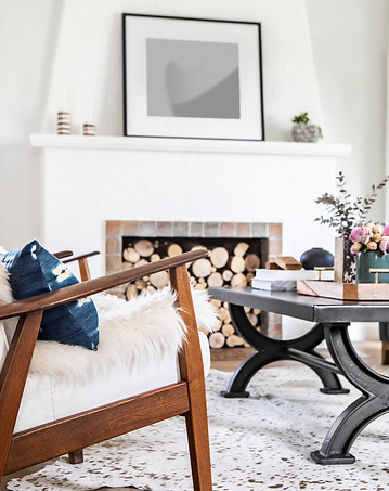 Cozy living room with mid-century armchair, fireplace, and modern coffee table with floral accents.