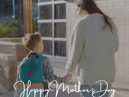 Mother and son walking towards school holding hands and chatting.