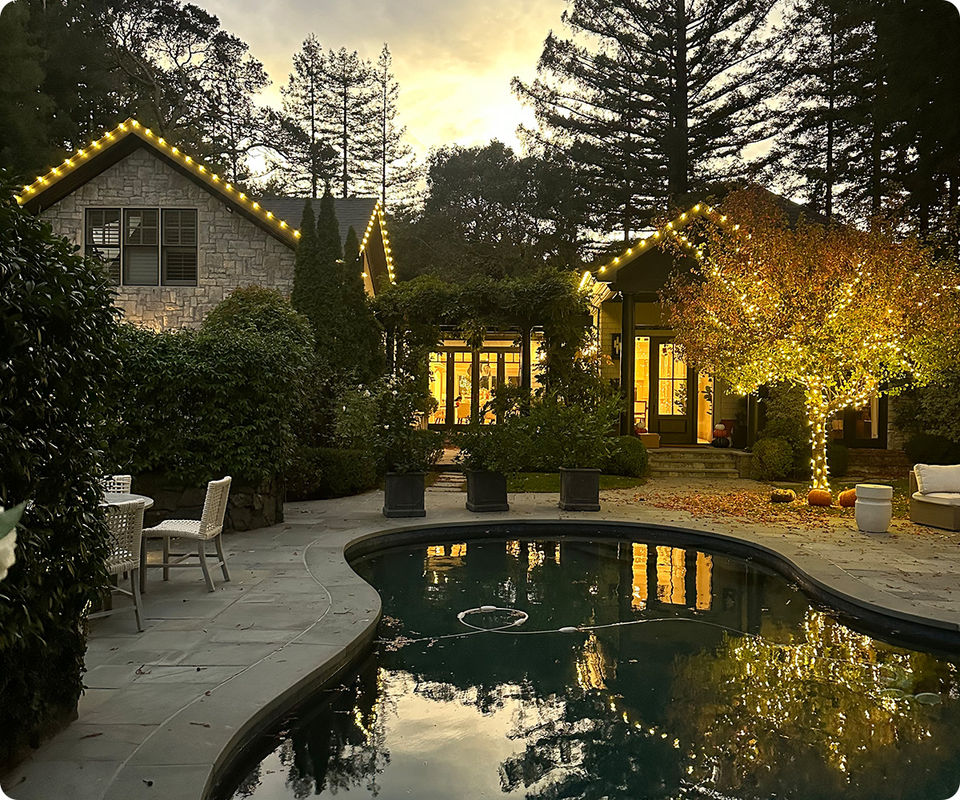 Poolside home with trees and landscaping illuminated by Christmas lights