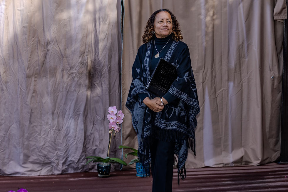 Wedding officiant Saundra Robinson holding her ceremony binder, standing beside pink orchids