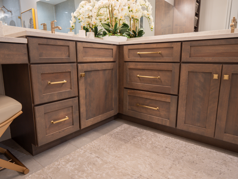 Bathroom remodel in Central Illinois featuring wood cabinetry, gold fixtures, smart storage solutions, and a walk-in shower.