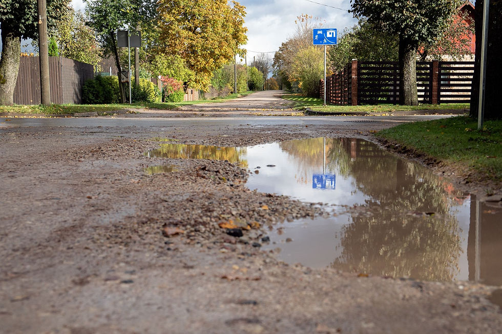 Muddy drive way and street with puddles of rain.